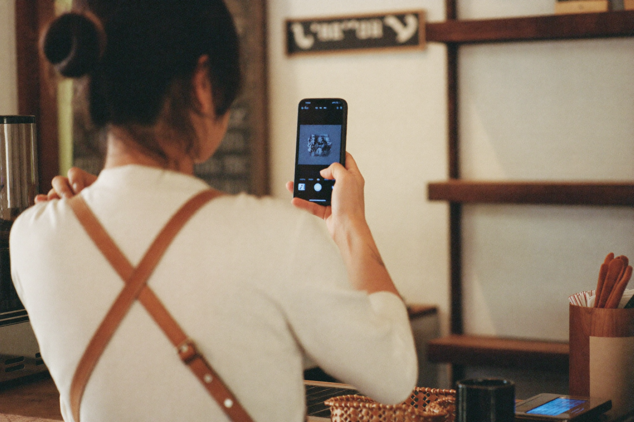 A café owner reviewing and approving a post on their phone before it goes live